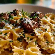 Close-up of Creamy Beef and Bowtie Pasta showing seared beef cubes, creamy parmesan sauce, and parsley over farfalle in a white bowl.