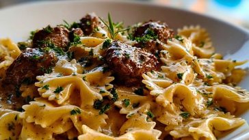 Close-up of Creamy Beef and Bowtie Pasta showing seared beef cubes, creamy parmesan sauce, and parsley over farfalle in a white bowl.