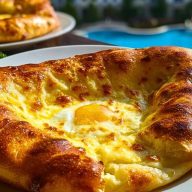 Golden-baked Easy Khachapuri with a runny egg center served on a white plate near a poolside, showcasing its crisp crust and melted cheese.