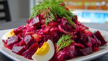Chunky Easy Russian Beet Salad served on a white plate with dill garnish and sliced boiled eggs around the edge.