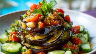 Layered Eggplant Salad with grilled eggplant, cherry tomatoes, cucumbers, and fresh herbs, garnished with mint, served by the poolside.